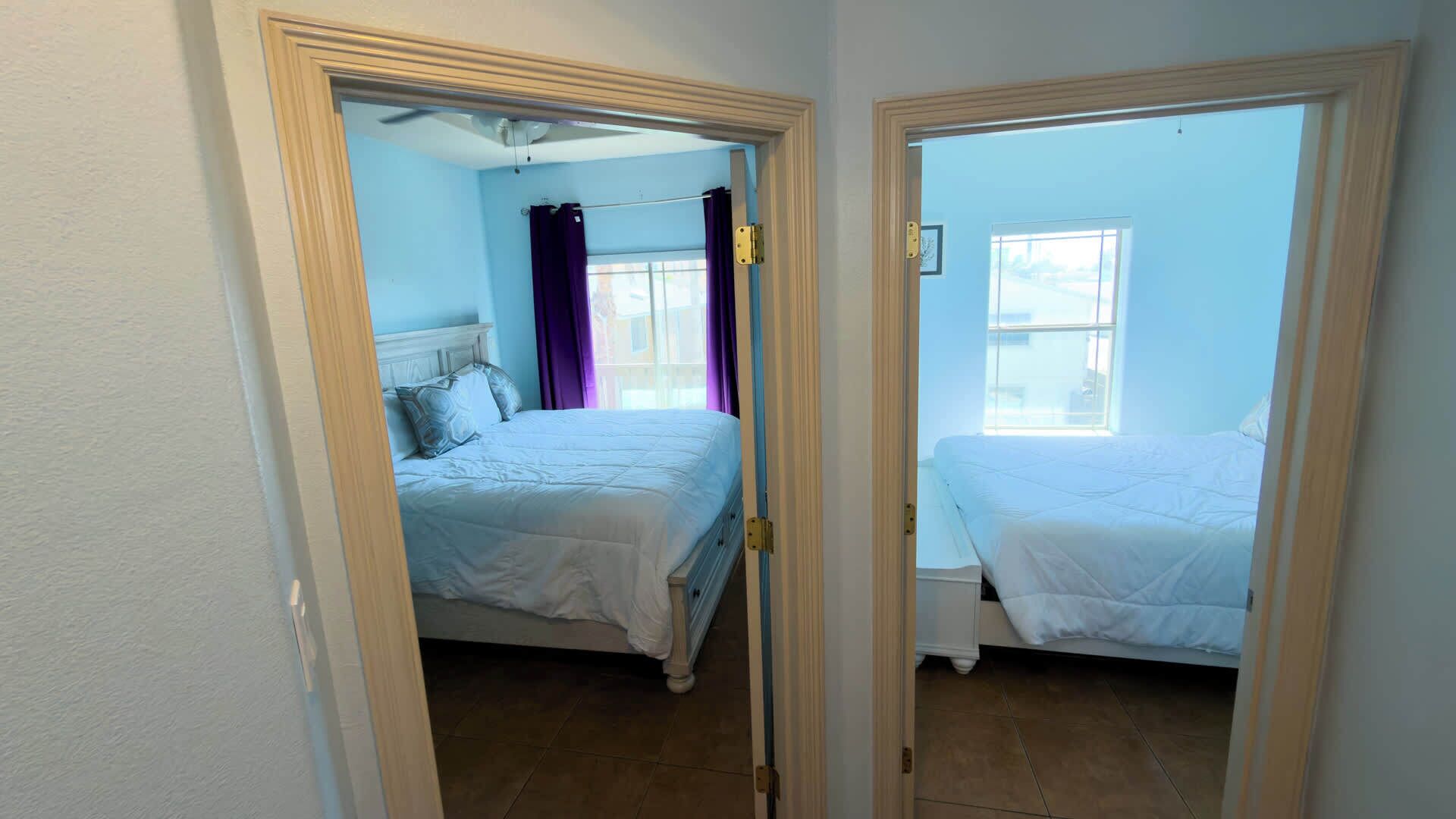 Une chambre avec deux lits, une fenêtre et une porte.