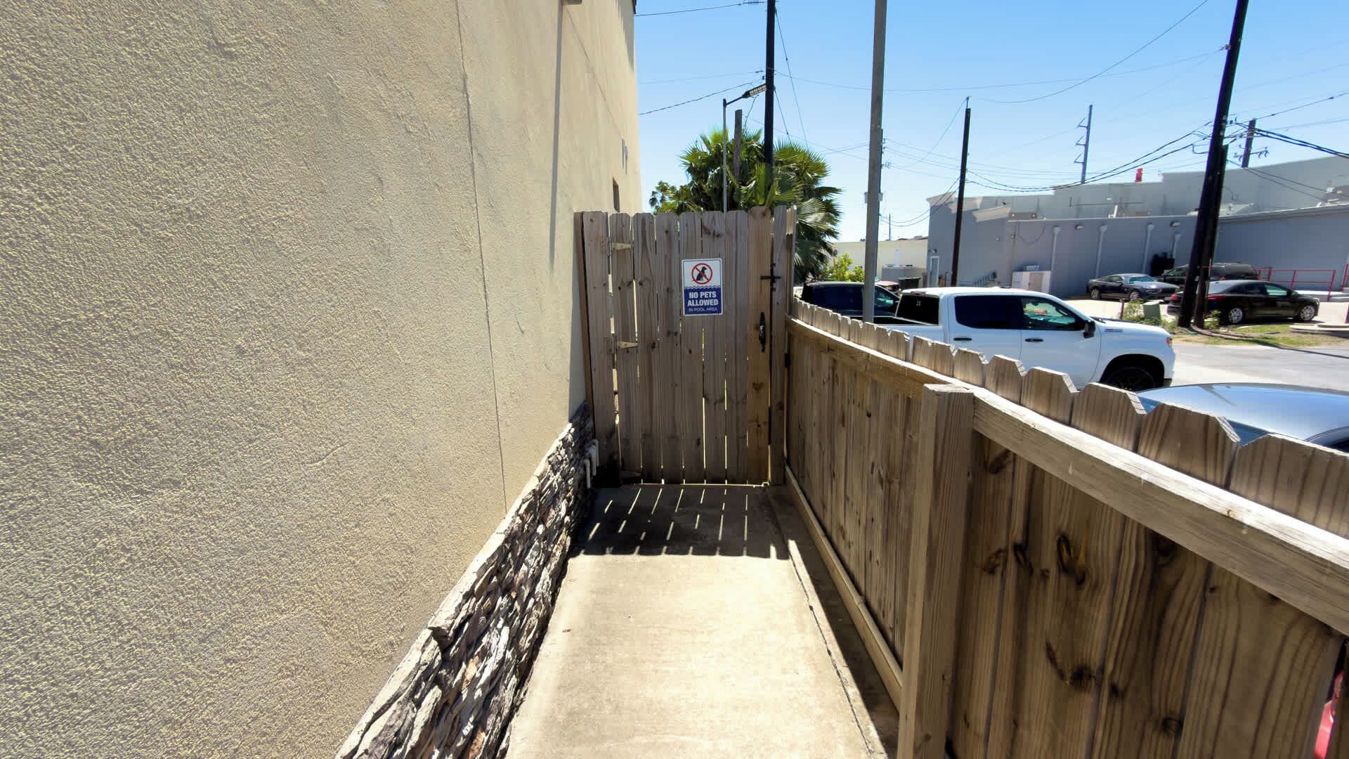Un étroit chemin de béton mène à une zone délimitée par une grille, sur laquelle est apposé un panneau indiquant qu'il est interdit d'y faire entrer des animaux.