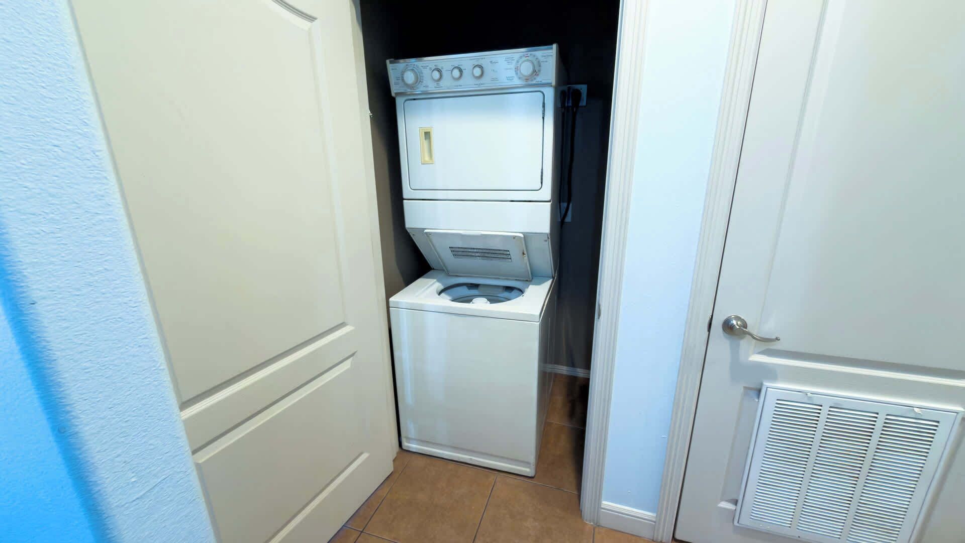 A laundry room with a washer and dryer, a door, and a vent.