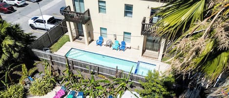 En bostadsbyggnad med en swimmingpool, flera balkonger och utsikt över parkerade bilar.