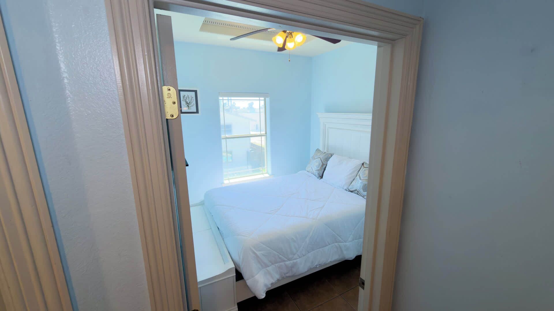Une chambre à coucher avec un lit, une fenêtre et un ventilateur de plafond.