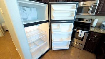 A kitchen with a double-door refrigerator, a microwave, an oven, and a sink.