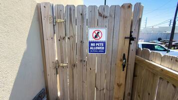 Een houten poort met een bord waarop staat 'GEEN DIEREN TOEGELATEN IN HET ZWEMBADGEBIED'.