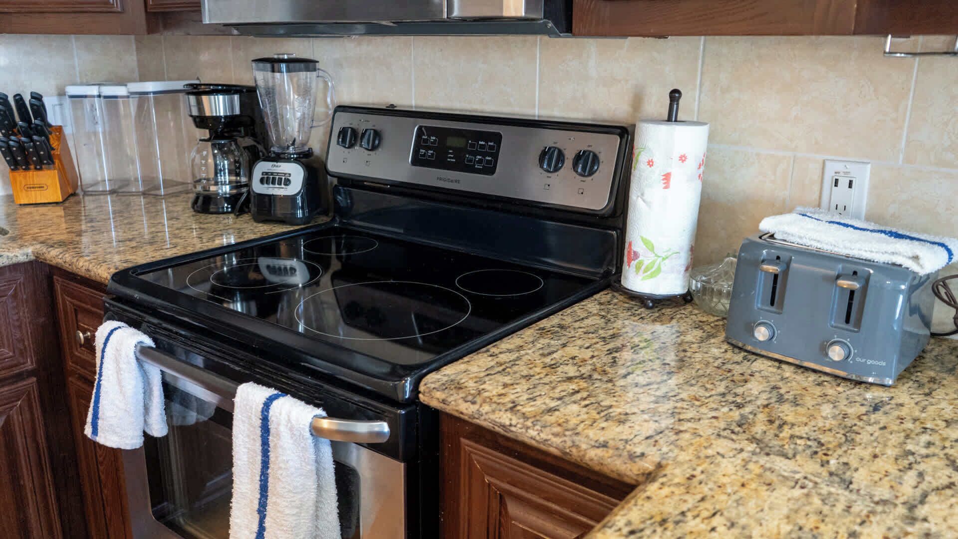 A kitchen with a stove, a toaster, a blender, and a coffee maker.