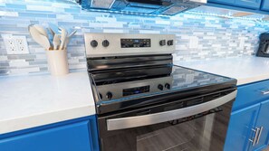 Une cuisine moderne dotée d’un four en acier inoxydable, de meubles bleus et d’un dosseret carrelé.