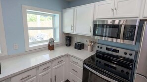 A kitchen with white cabinets, a microwave, an oven, a toaster, and a coffee maker. - New 5BR Remodel, Heated Pool, Game Room (South Padre Island)