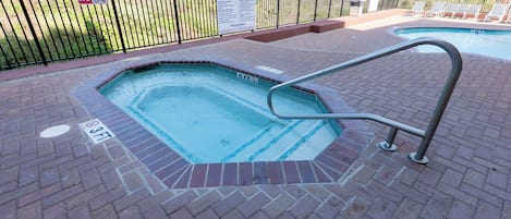A hot tub with a metal ladder, surrounded by a brick patio.