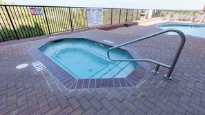 A hot tub with a metal ladder, surrounded by a brick patio. - Direct Beachfront Condo-jacuzzi-elevator-spi (South Padre Island)