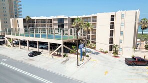 Un hotel de varios pisos con piscina en la azotea, garaje de estacionamiento y vistas al océano.