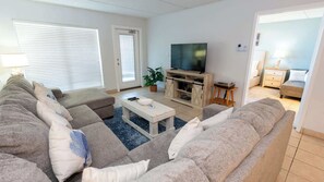 A living room with a sofa set, a coffee table, a TV, and a small side table. - Direct Beachfront Condo-jacuzzi-elevator-spi (South Padre Island)