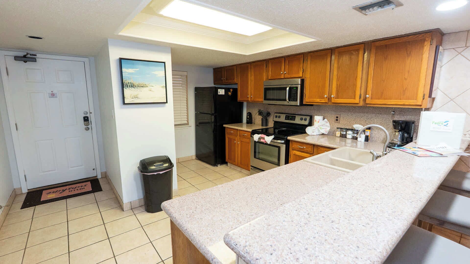A kitchen with wooden cabinets, a stainless steel refrigerator, an oven, a microwave, and a sink.