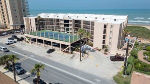 A multi-story building with a rooftop tennis court, parking area, and a view of the ocean. - Direct Beachfront Condo-jacuzzi-elevator-spi (South Padre Island)