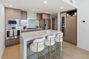 A modern kitchen with a central island, stainless steel appliances, and a bar stool seating arrangement.