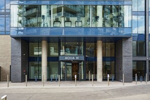 A modern building with a glass facade and the sign 'AQUA III' indicating a hotel or similar establishment.