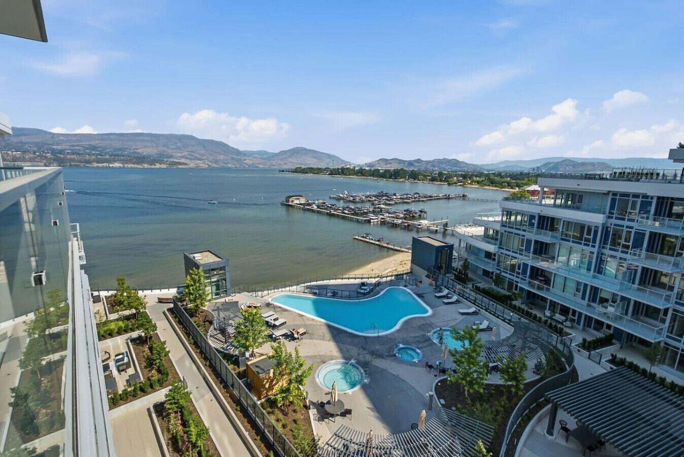 A hotel with a pool area, a marina, and a view of the water and mountains.