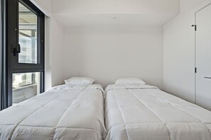 A room with two beds, a window, and a door. - Luxury Beachfront | 2 Bed | Pool & Hot Tub | Gym (Kelowna)
