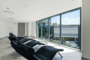 A modern waiting area with black chairs, a glass wall, and a view of a building.