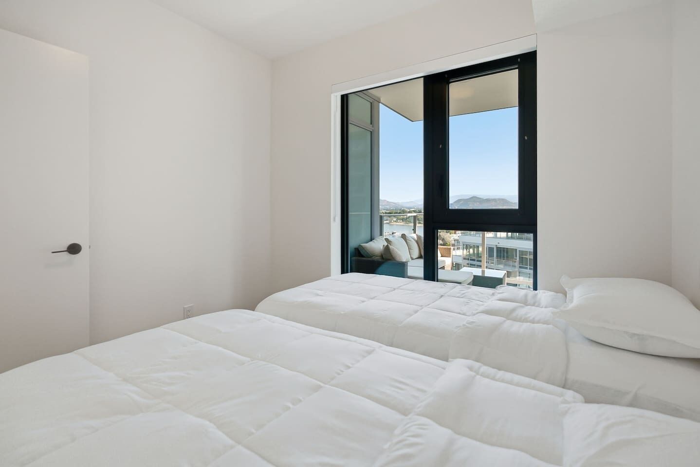 Un dormitorio moderno con una ventana grande, una cama y vistas a un paisaje urbano.