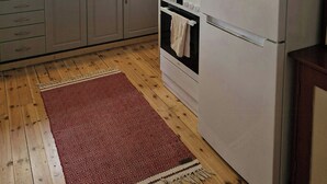 Eine Küche mit Holzboden, einem Kühlschrank, einem Herd und einem Fenster mit Vorhang.