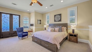 A bedroom with a bed, a chair, a nightstand, and a ceiling fan.