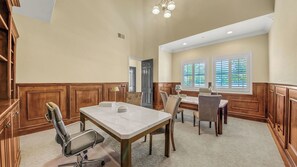A dining area with a marble table, chairs, and a chandelier.