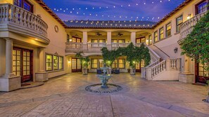 A courtyard with a central fountain, multiple balconies, and a staircase leading to an upper level.