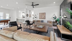A modern living room with a pool table, leather sofas, a coffee table, and a dining area with bar stools. - Luxury 7BR - Heated Pool, Hot Tub, Pet Friendly (Austin)