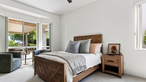 A bedroom with a bed, a nightstand, a chair, and a window.