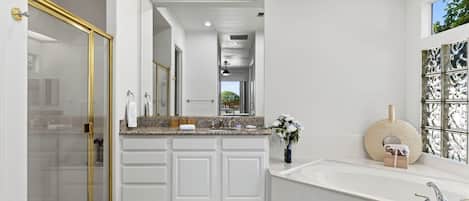 A modern bathroom with a walk-in shower, a freestanding bathtub, and a vanity with a granite countertop.