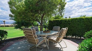 An outdoor patio with a round table and four chairs, surrounded by a well-maintained hedge and a tree. - Palm & Par by Avantstay Golf Views + Patio BBQ Mins to Indian Wells (Palm Desert)