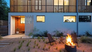 A modern two-story house with a blue exterior, a wooden balcony, and a fire pit in the front yard. - Elizabeth House by Avantstay Saltwater Plunge Pool + Casita + Firepit (Austin)