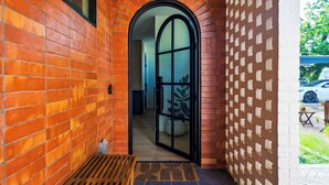 A brick exterior with a wooden bench, a glass door, and a white brick wall with a pattern. - Elizabeth House by Avantstay Saltwater Plunge Pool + Casita + Firepit (Austin)