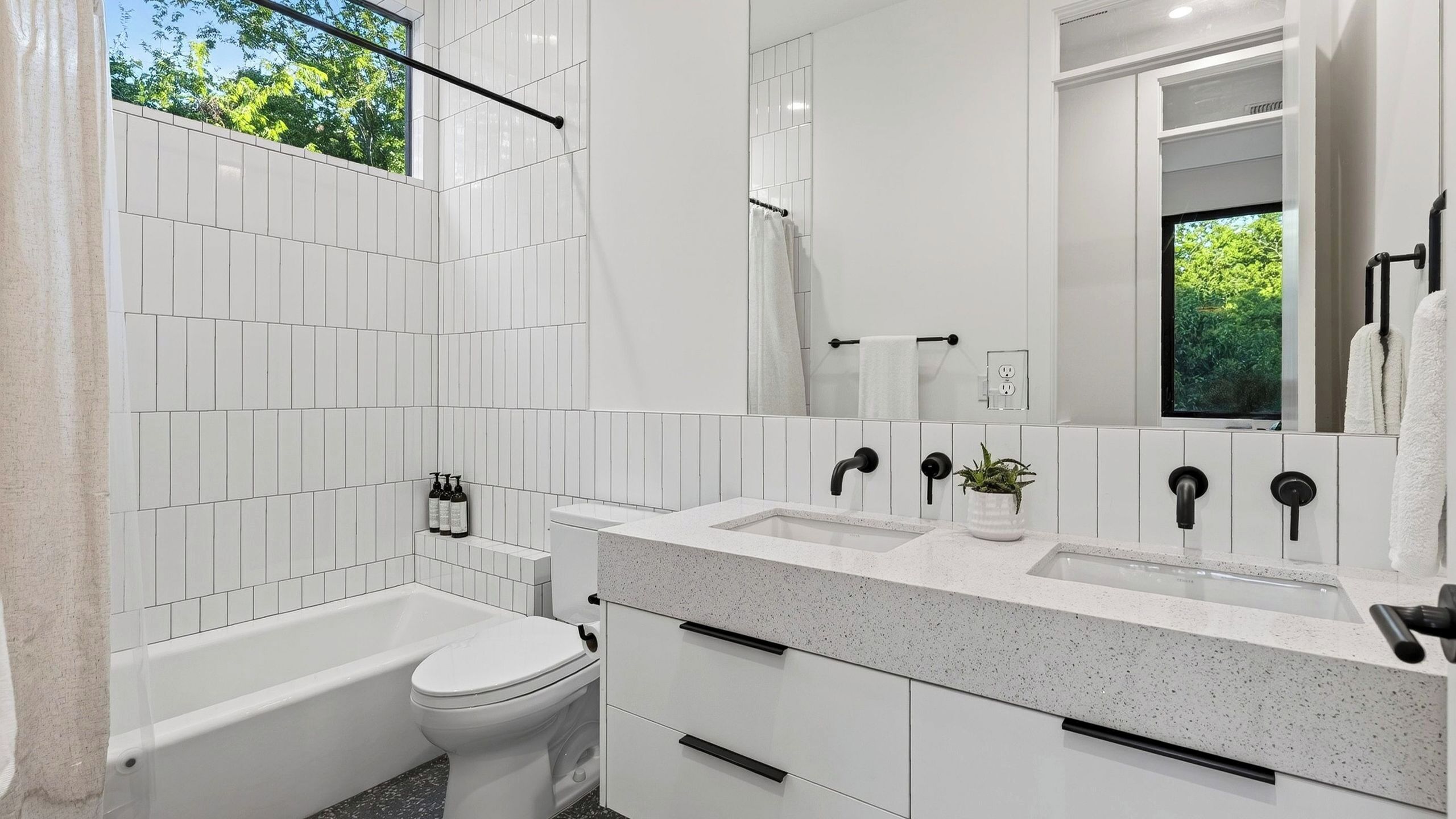 Ein modernes Badezimmer mit Badewanne, Toilette und einem Doppelwaschtisch.