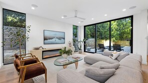 Una sala de estar moderna con chimenea, asientos cómodos y grandes ventanales con vistas al exterior.