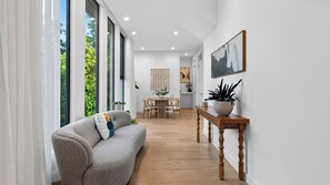 Ein modernes Interieur mit einer Couch, einem Esstisch und Topfpflanzen.