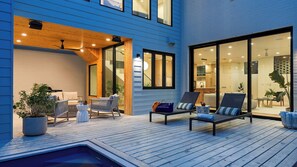 Eine moderne Terrassengestaltung mit Sitzgelegenheiten, einem Pool und Blick ins Haus.