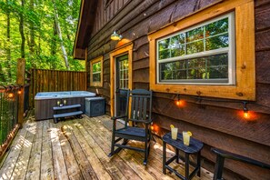 A wooden cabin with a deck, a hot tub, and a seating area with a table and chairs. - Havenheart Smoky Mtns Romantic Treehouse (Sevierville)