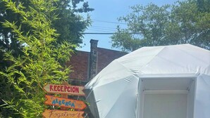 Una carpa con una puerta, rodeada por un panel de señalización que indica el camino a diferentes servicios.