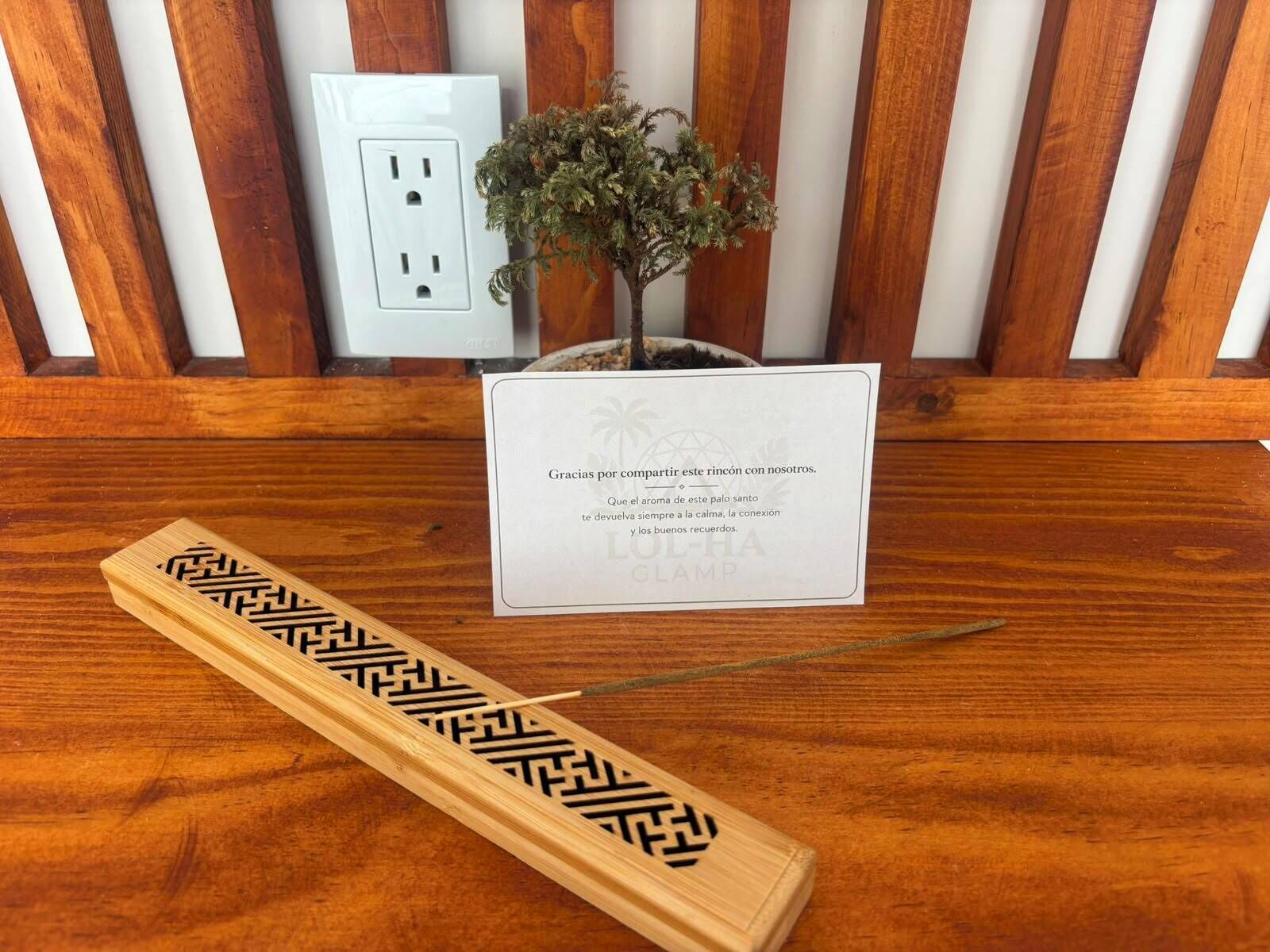 A wooden table with a matchstick, a small potted plant, and a card with text.