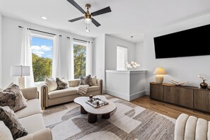 A modern living room with a sofa, coffee table, and a flat-screen TV mounted on the wall. - Ovation @ The New Cumberland Resort (Nashville)