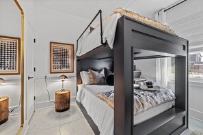 A bunk bed with a dark headboard, a bedside table with a lamp, and a framed artwork on the wall. - Ovation @ The New Cumberland Resort (Nashville)