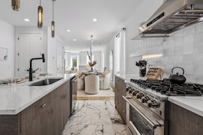 A modern kitchen with a central island, stainless steel appliances, and a marble floor. - Ovation @ The New Cumberland Resort (Nashville)