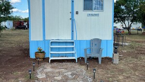 Un piccolo edificio a un piano con una porta e una finestra blu, una panca di legno all'esterno e un vialetto in pietra che conduce all'ingresso.