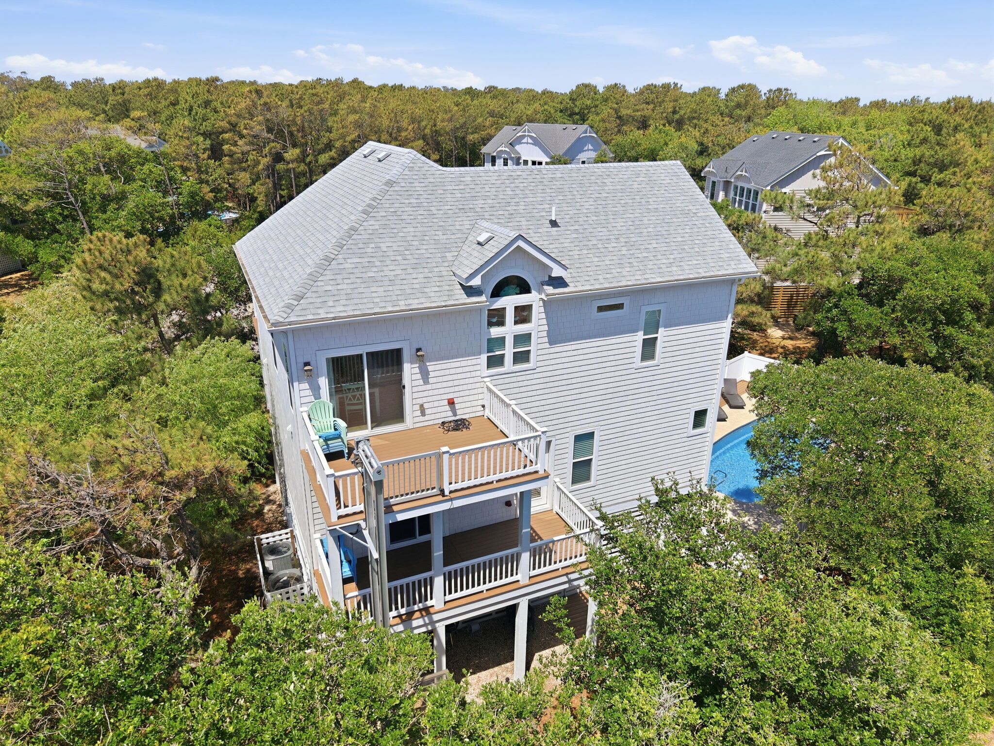 A two-story house with a deck and a swimming pool.