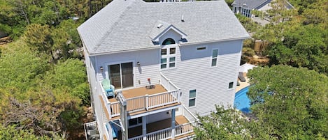 A two-story house with a deck and a swimming pool.