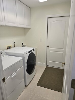 Une buanderie équipée d’un lave-linge et d’un sèche-linge à chargement frontal, d’une porte et d’une petite marche menant à la porte.