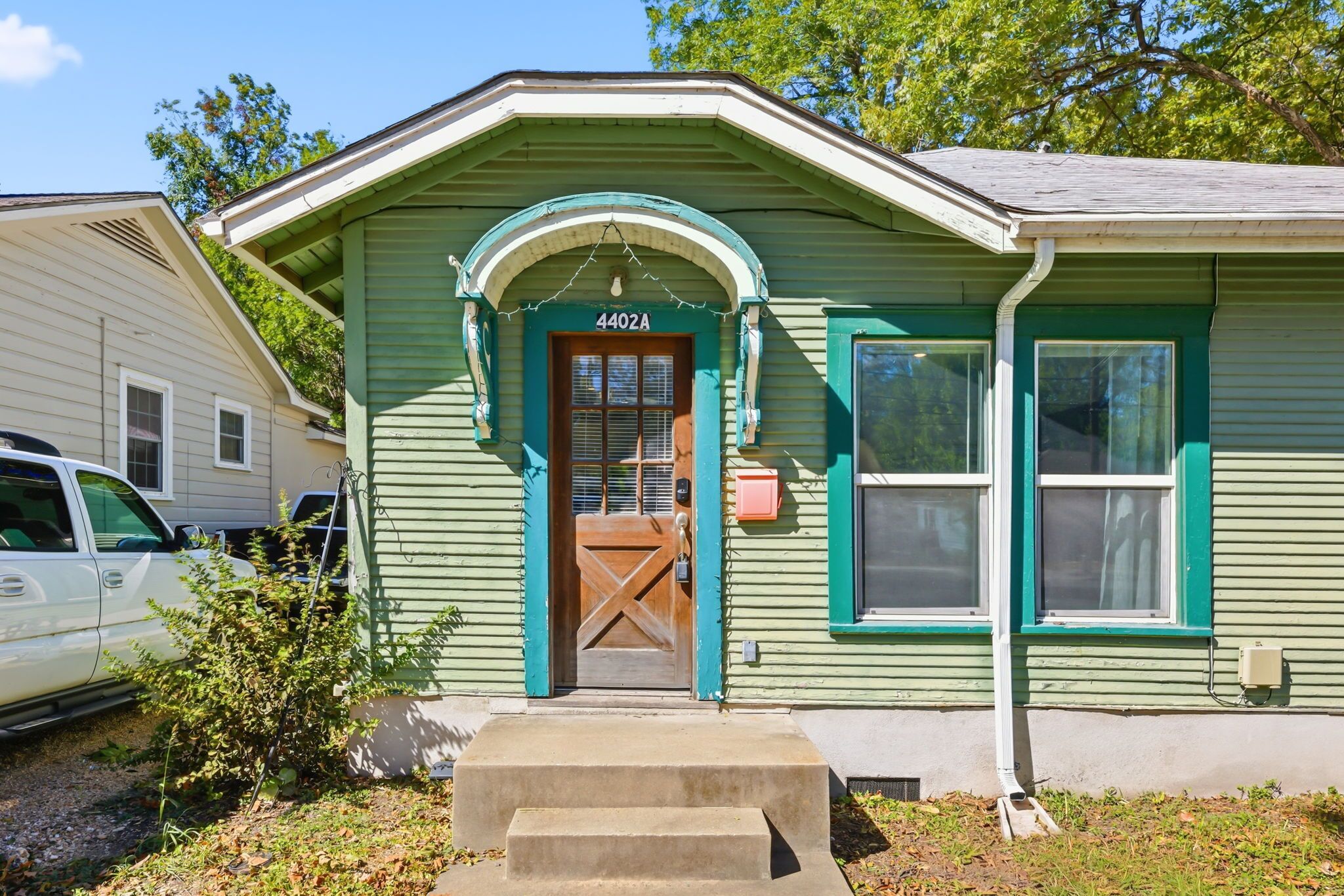 Une maison verte avec une porte en bois et des marches menant à l’entrée.