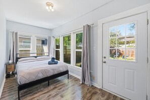 A bedroom with a bed, a nightstand, and a door with a window. - HydePark Stay  UT Modern 2BR/1.5BA Yard & Parking (Austin)