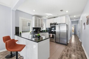 A modern kitchen with white cabinets, stainless steel appliances, and a central island. - HydePark Stay  UT Modern 2BR/1.5BA Yard & Parking (Austin)