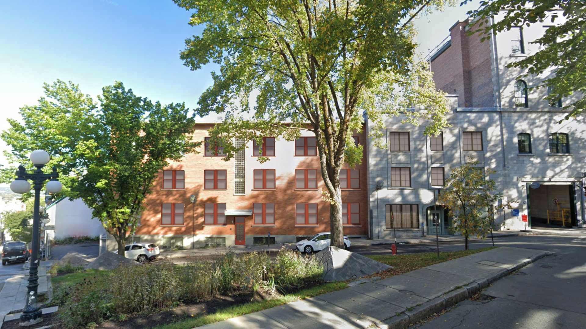 A multi-story building with a brick facade, large windows, and a fire hydrant on the sidewalk.